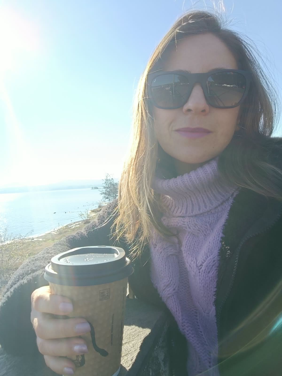 Constanza junto a la playa sosteniendo un café